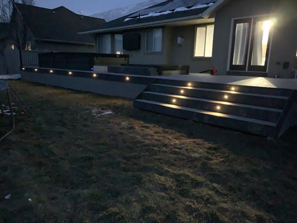 A custom deck designed to surround a swim spa and hot tub, complete with stairs and built-in lighting for safety and ambiance—perfect for relaxing day or night.