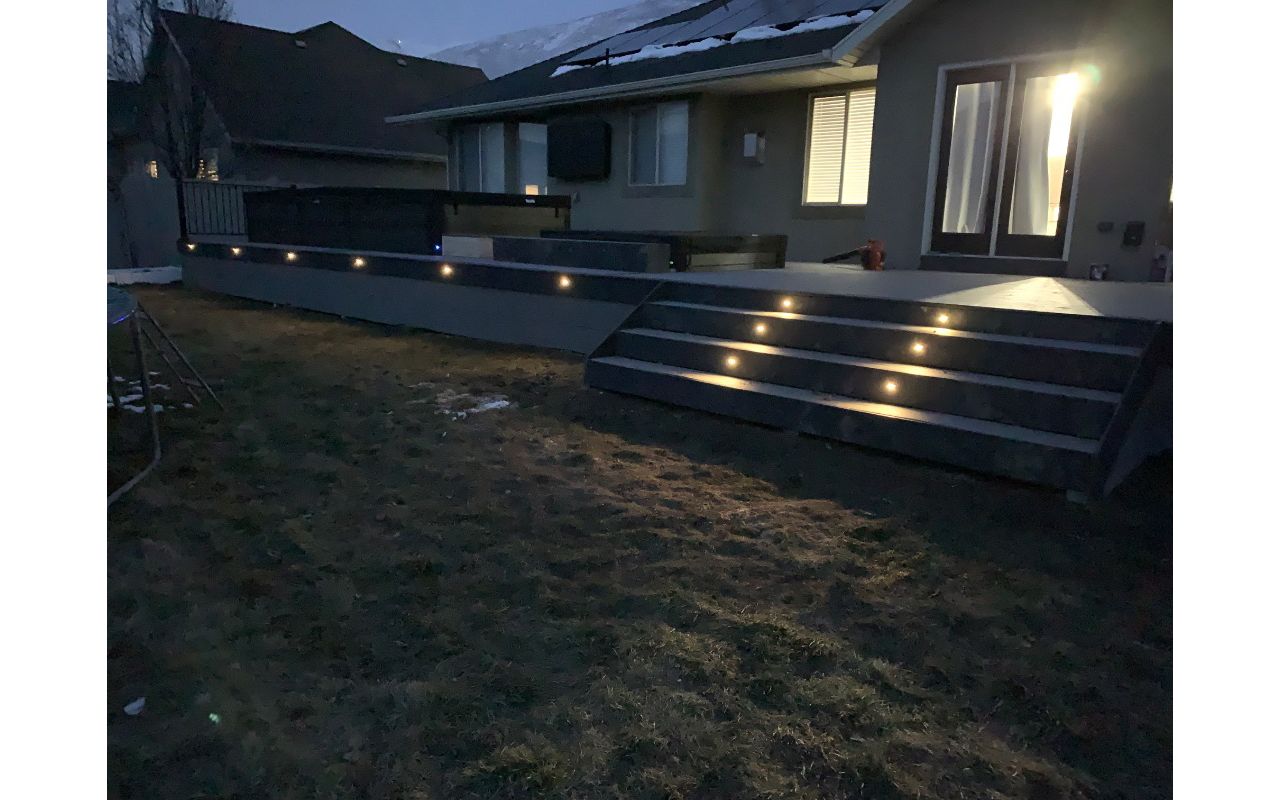 A custom deck designed to surround a swim spa and hot tub, complete with stairs and built-in lighting for safety and ambiance—perfect for relaxing day or night.