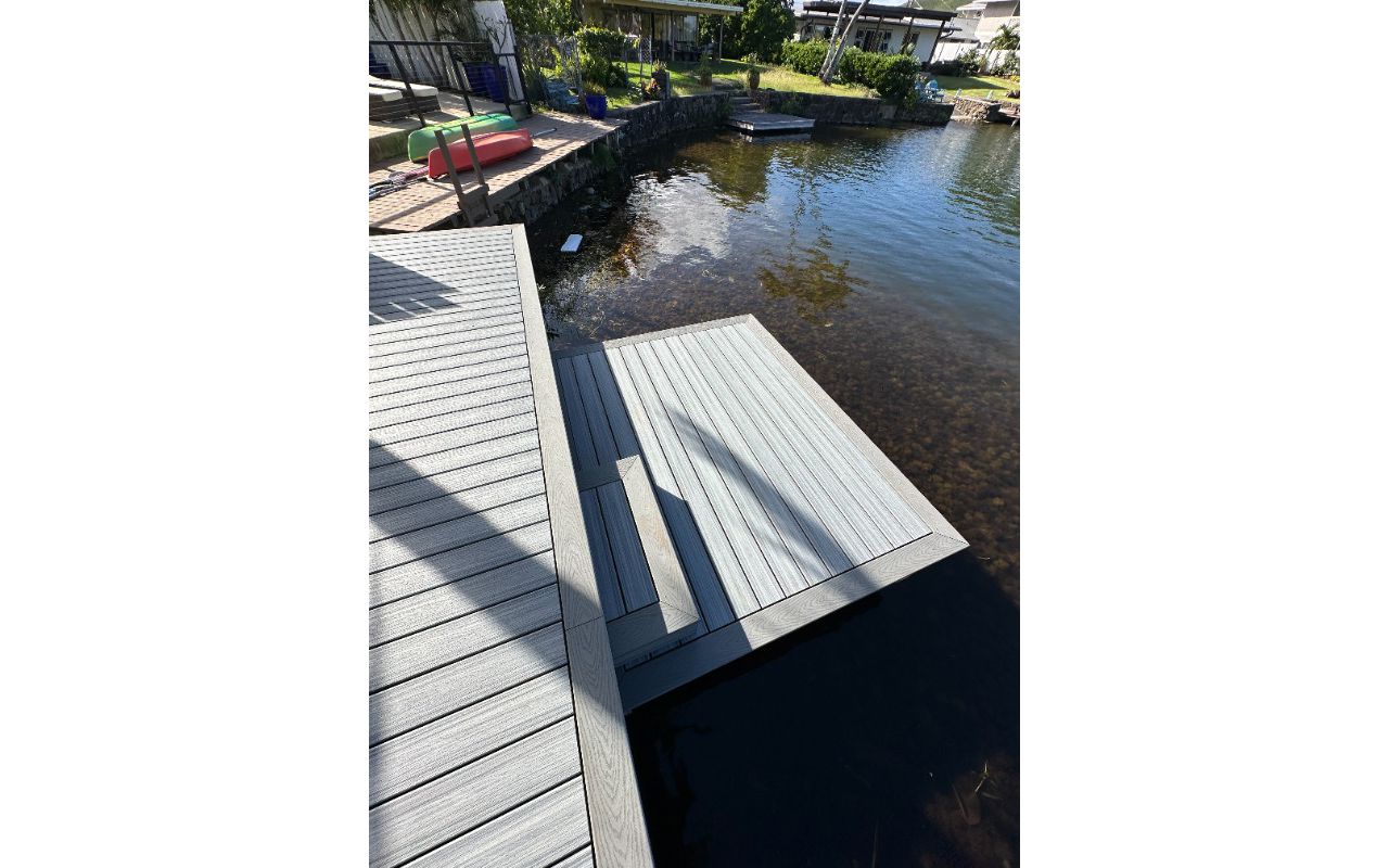 The Kailua deck features Foggy Wharf decking with a Pebble Grey picture frame border and custom steps, designed for a sleek and modern look.