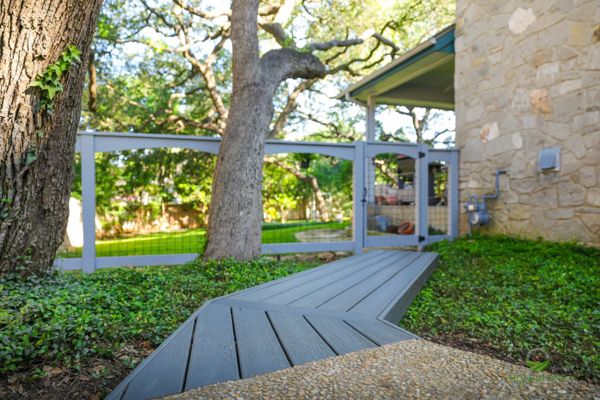 Trex composite walkway winding to a gated entry under a live oak