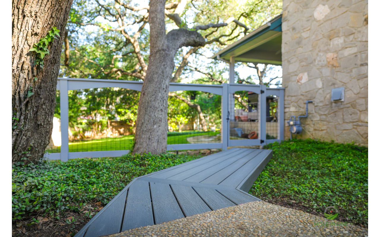 Trex composite walkway winding to a gated entry under a live oak