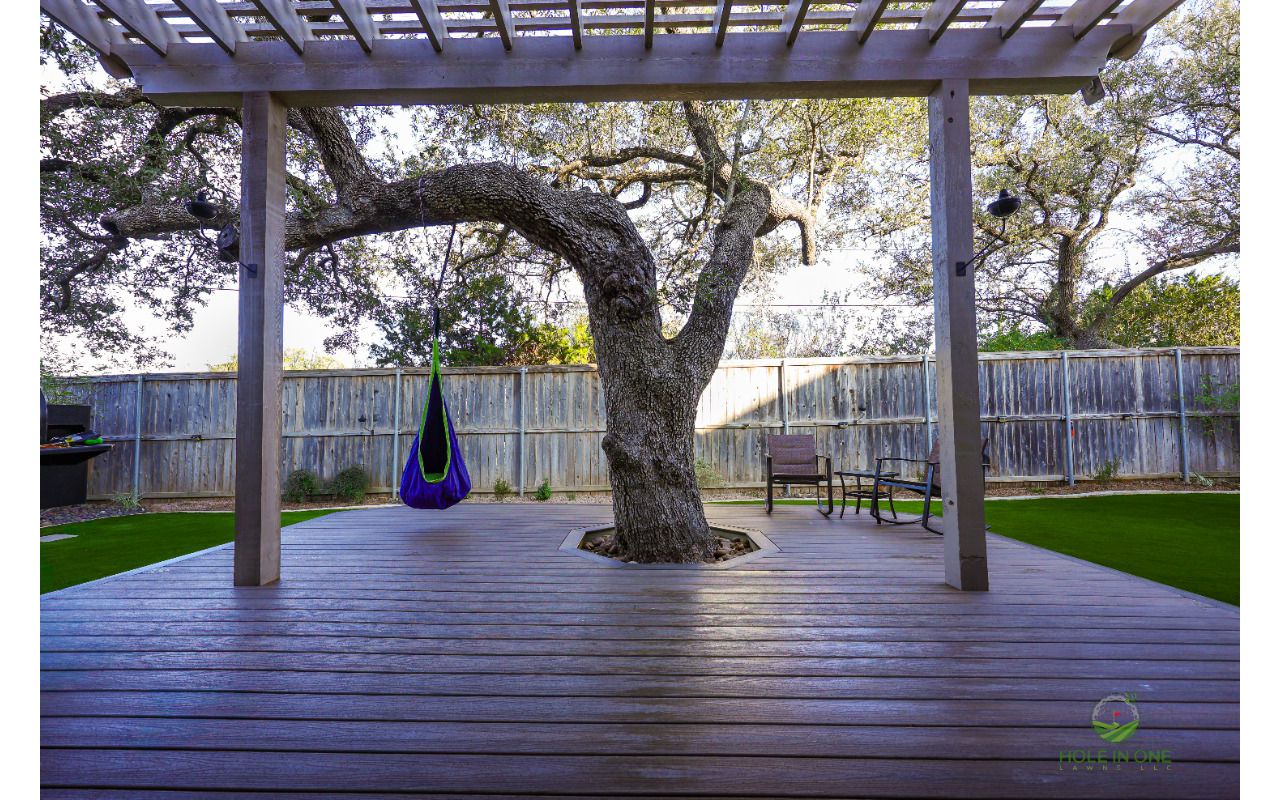 Trex composite deck built around a live oak with an open tree cutout, under a pergola in San Antonio