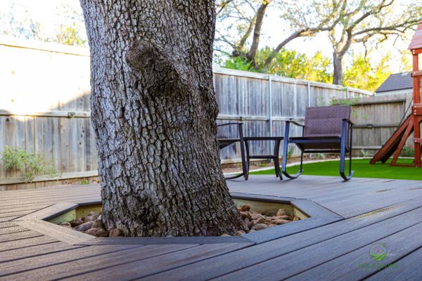 Custom tree cutout in a Trex deck with a river rock border to protect the live oak trunk