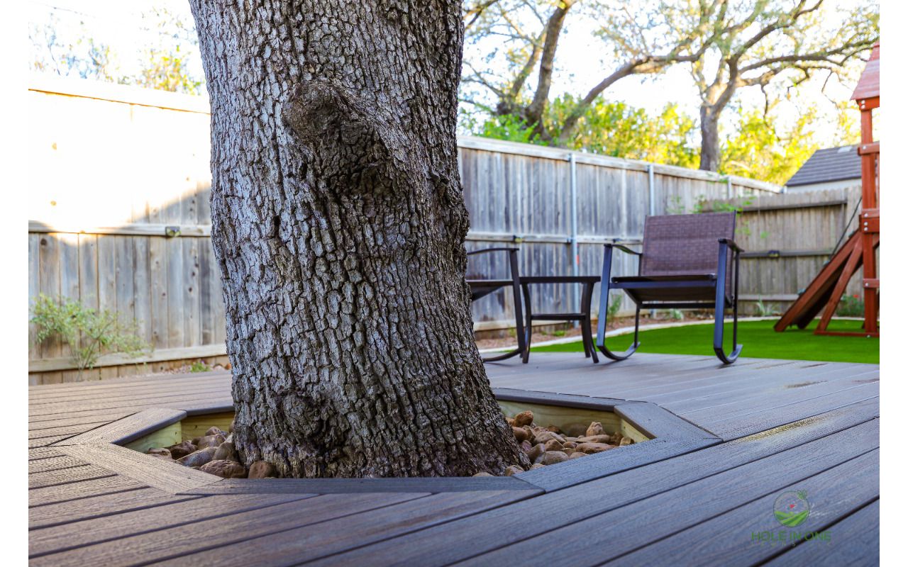 Custom tree cutout in a Trex deck with a river rock border to protect the live oak trunk