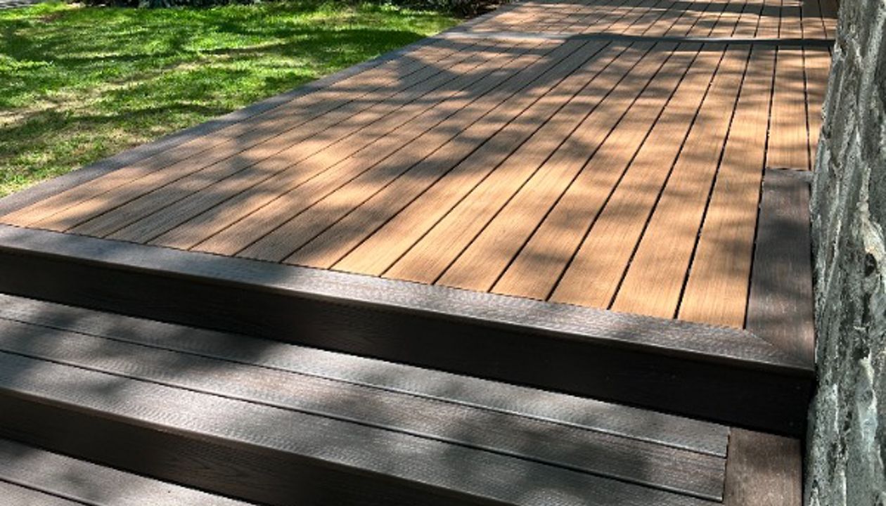 The deck is made with Trex Transcend® Tiki Torch decking, Lava Rock trim, and black Trex Signature® railing, designed for a seamless and elegant finish.
