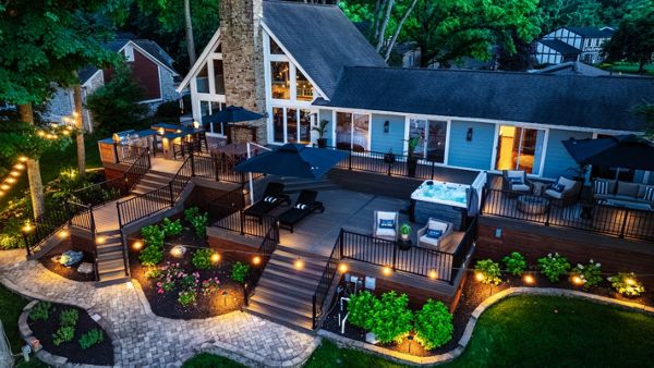 Multi-level Trex deck illuminated with landscape and ambient lighting, creating a dramatic nighttime outdoor living space.
