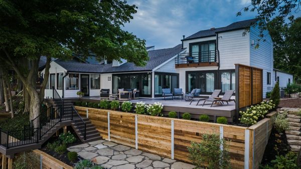 Spacious Trex deck with lounge seating, custom wood privacy screen, and tiered landscape walls overlooking the lake.