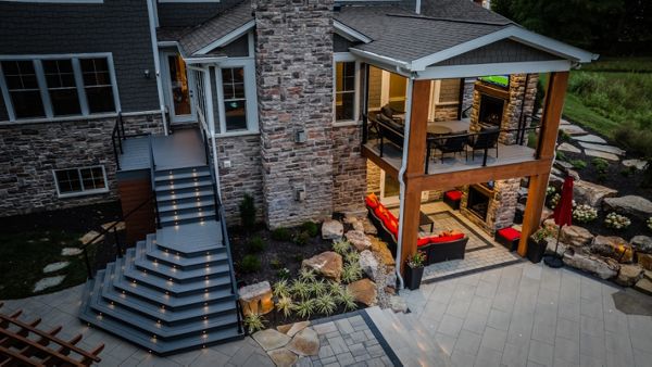 Covered outdoor living space with stone fireplace, composite decking, and integrated patio for year-round entertaining.