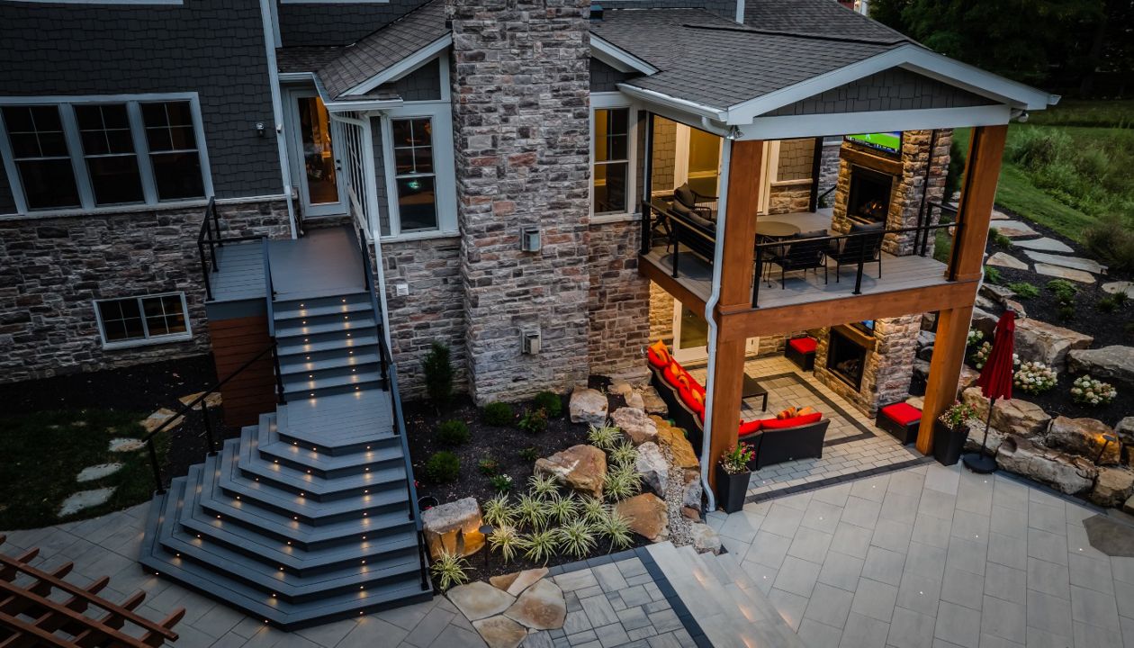 Covered outdoor living space with stone fireplace, composite decking, and integrated patio for year-round entertaining.