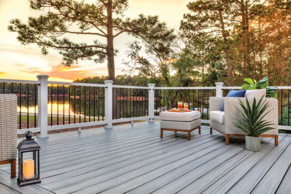 A deck in the Trex color Foggy Wharf with a scenic lake in the background with the sunsetting over the tree-line. 