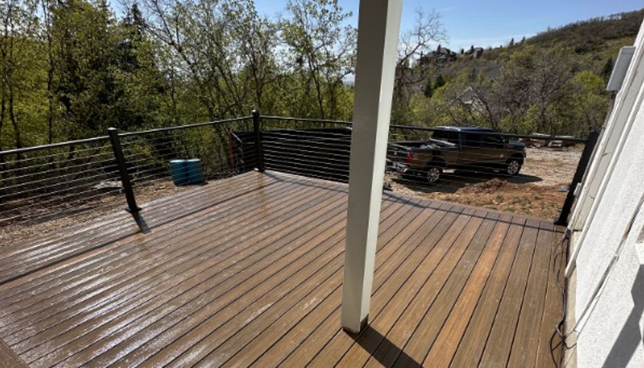 Nestled in a backyard forest, this Cinnamon Cove Trex® deck with cable railing blends natural beauty with modern durability — built to enjoy the outdoors in style.
