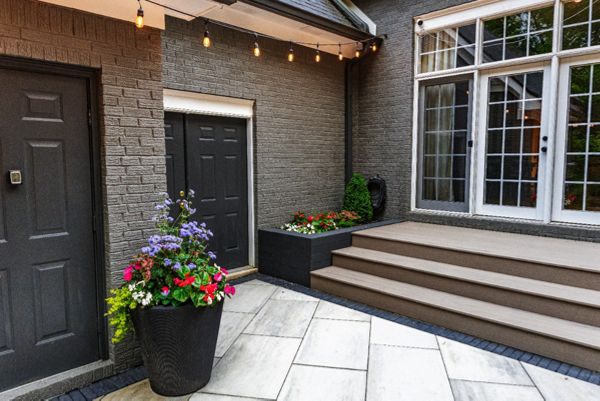Clean transition from patio to composite deck with modern planters and warm café lighting for an intimate outdoor space.