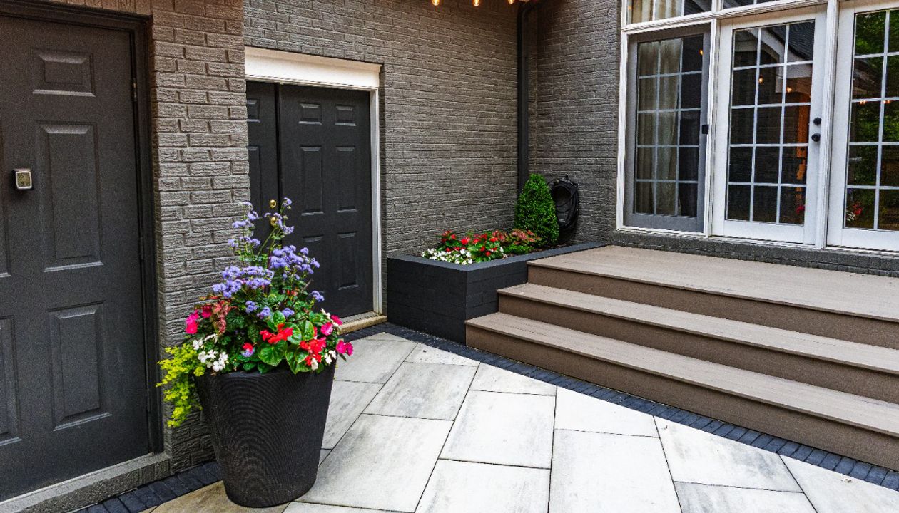 Clean transition from patio to composite deck with modern planters and warm café lighting for an intimate outdoor space.