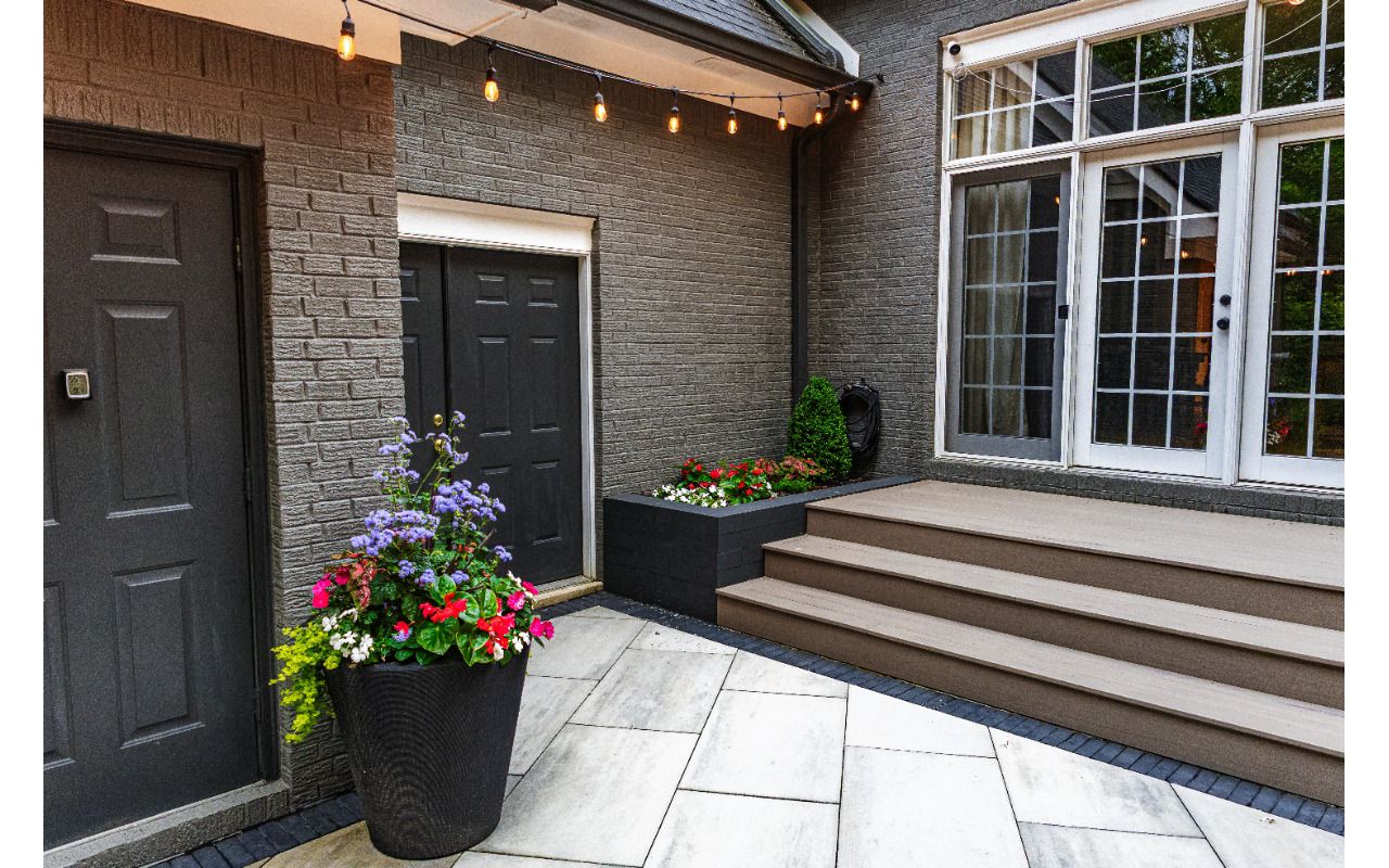 Clean transition from patio to composite deck with modern planters and warm café lighting for an intimate outdoor space.