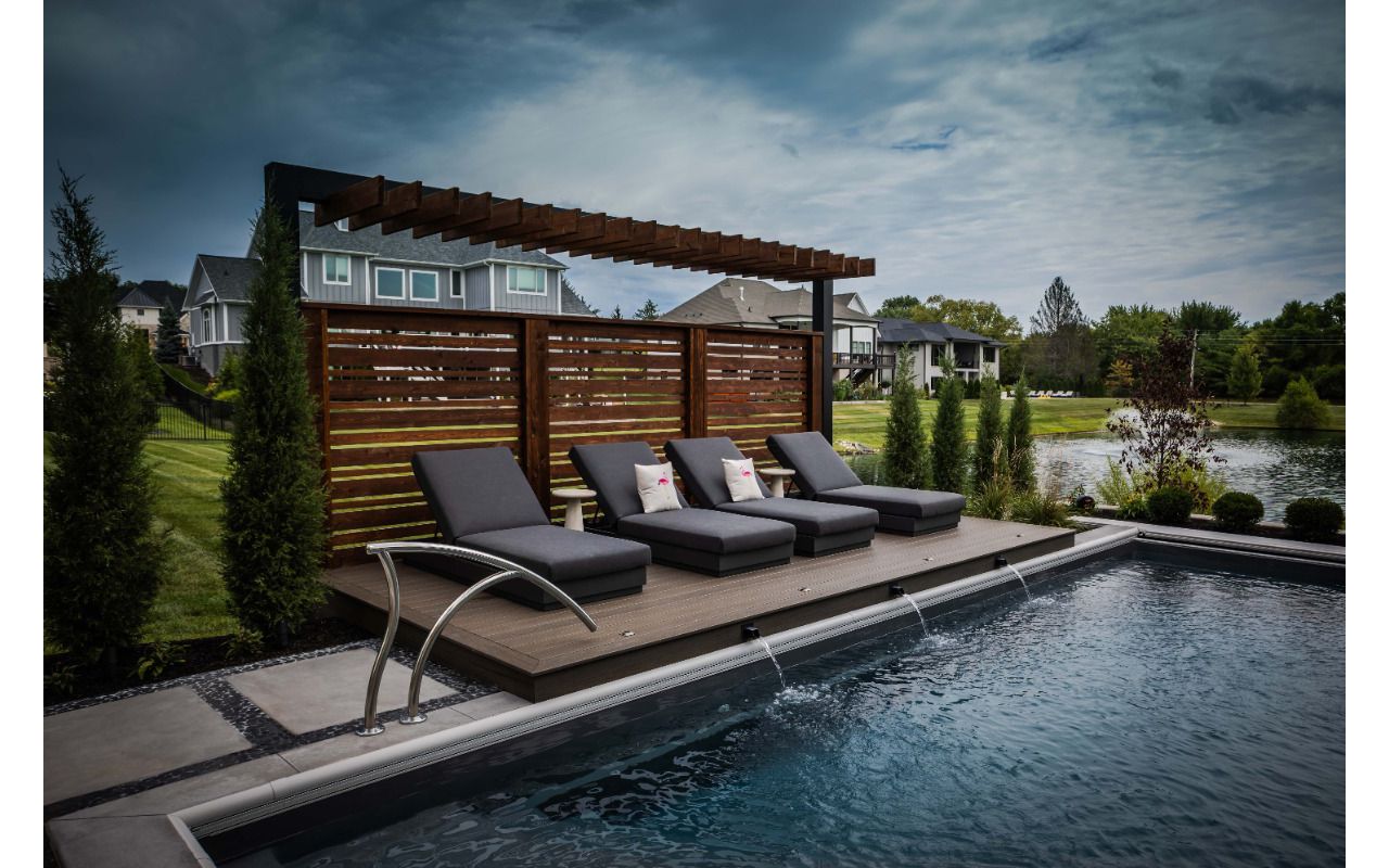 Poolside composite lounge deck with modern pergola and privacy screen creating a relaxing resort-style seating area.