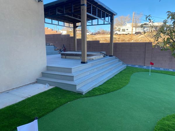 From wraparound stairs to the putting green — this Trex Pebble Grey deck turns your backyard into a private resort. A sunken hot tub, pergola shade, and a view worth the walk make every step a destination.