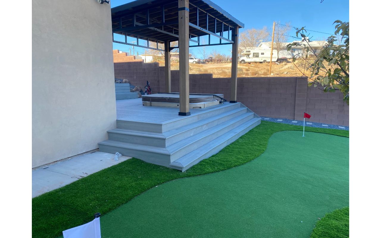 From wraparound stairs to the putting green — this Trex Pebble Grey deck turns your backyard into a private resort. A sunken hot tub, pergola shade, and a view worth the walk make every step a destination.