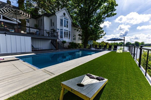 Large poolside Trex deck featuring integrated turf area for recreation, modern railing, and unobstructed lakefront views.