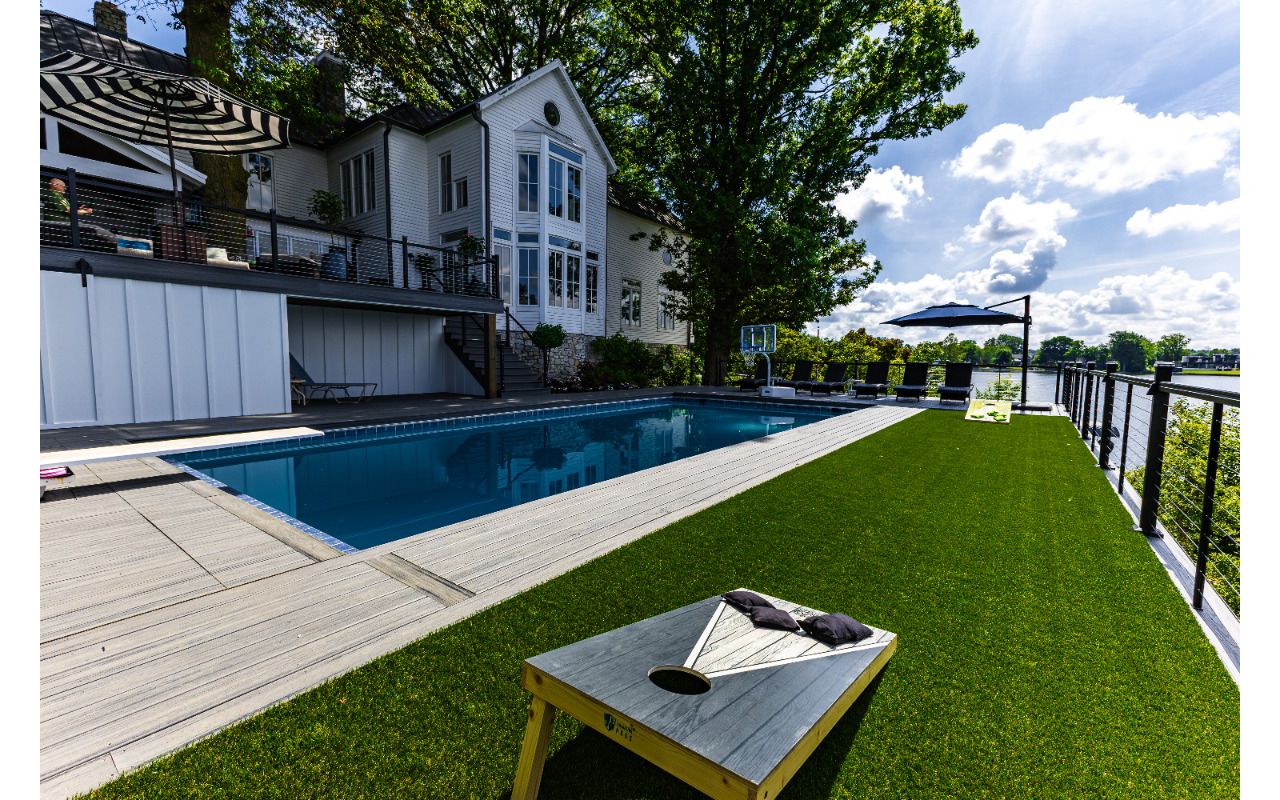 Large poolside Trex deck featuring integrated turf area for recreation, modern railing, and unobstructed lakefront views.