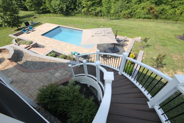 Curved deck steps down to tiered patio and pool area Highland, MD