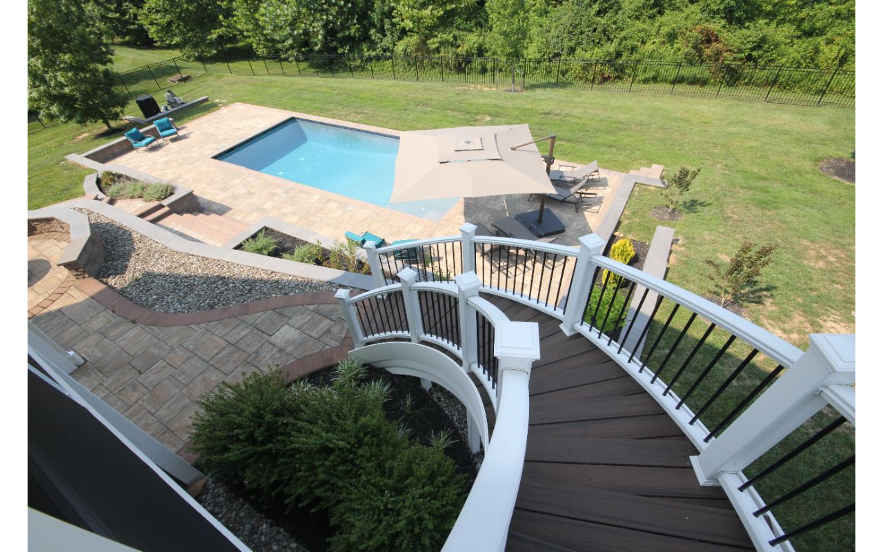 Curved deck steps down to tiered patio and pool area Highland, MD