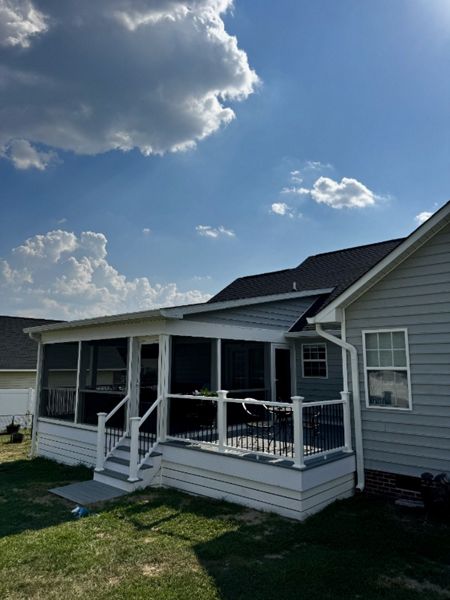 New custom Trex Foggy Wharf deck featuring white vinyl railing, black round spindles, and a matching breaker board. Expert deck construction in Lillington, North Carolina.