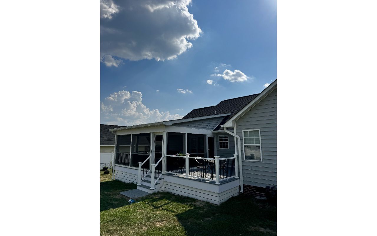 New custom Trex Foggy Wharf deck featuring white vinyl railing, black round spindles, and a matching breaker board. Expert deck construction in Lillington, North Carolina.