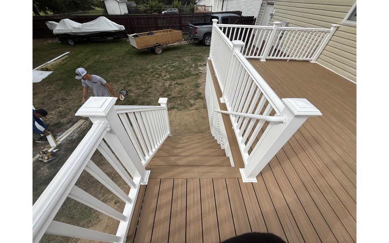 New custom Trex Golden Hour deck featuring white composite railings, color-matched face screws, and a white privacy diamond lattice underpinning. Expert deck construction in Cameron, North Carolina.