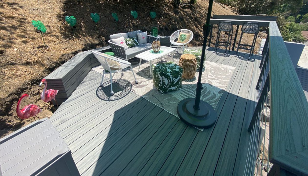 Trex Transcend hilside deck with a retaining bench and a bar in Island Mist