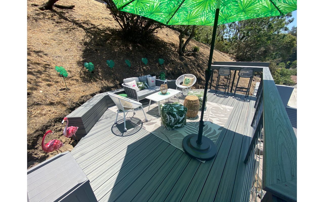 Trex Transcend hilside deck with a retaining bench and a bar in Island Mist