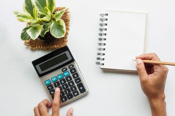 First person perspective of hands on a table trying to calculate costs.