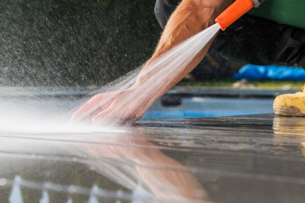 A closeup of a deck as someone power washes it.