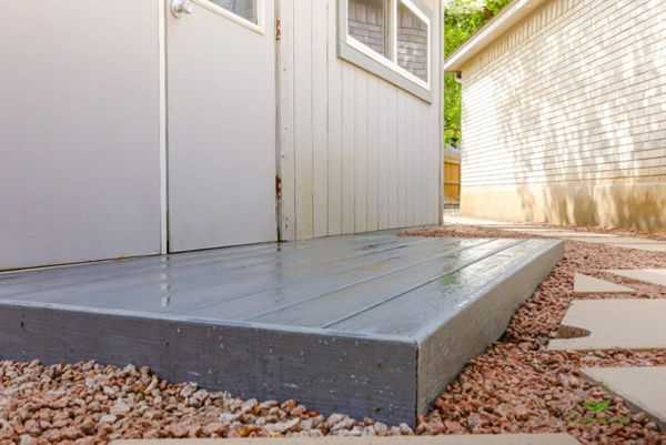 Low-profile Trex composite landing with fascia set in gravel beside a home