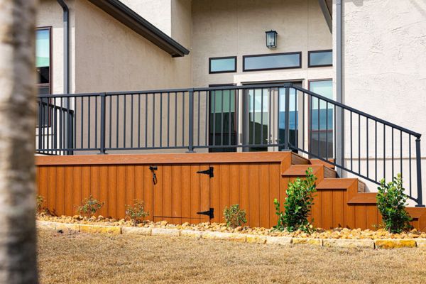 Raised Trex deck with black metal railing and Trex skirting with a storage access door