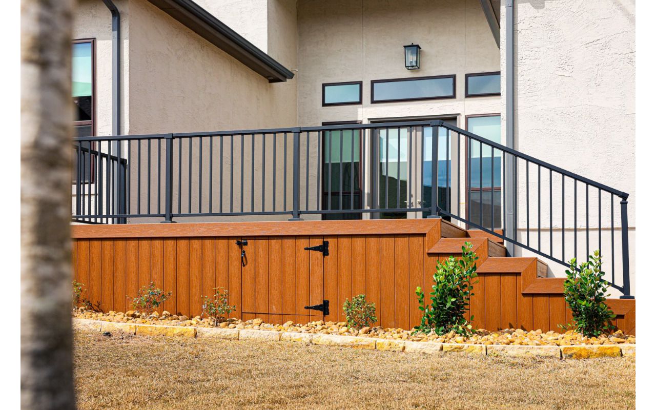 Raised Trex deck with black metal railing and Trex skirting with a storage access door