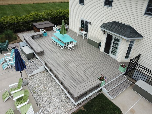 Grey Trex deck with bright deck furniture and a hot tub. 