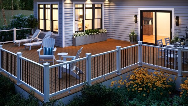 Deck with outdoor furniture and a composite railing lit at early evening. 