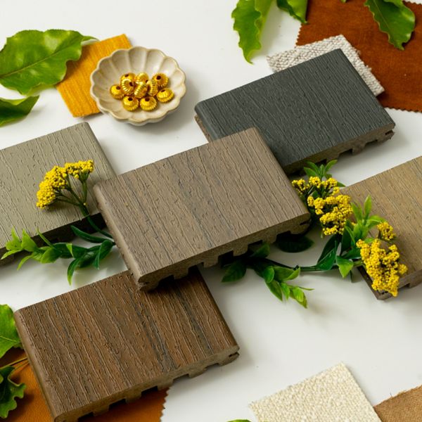 A selection of wood texture samples is arranged in a circular pattern, surrounded by colorful fabric swatches and green leaves. Yellow flowers and a small dish containing golden capsules add decorative elements to the composition. The scene is set on a white background, highlighting the natural and earthy tones of the materials.