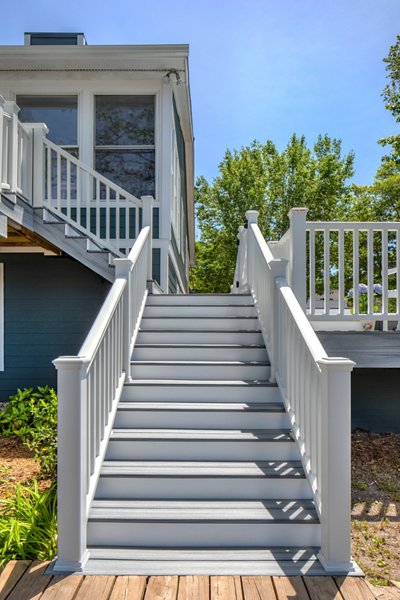 Stairs leading up to a two story deck, with Trex Transcend railing in white lining the stairs and deck.