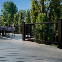 A spacious outdoor deck features a contemporary dining table surrounded by multiple chairs, set against a backdrop of lush green trees and residential homes. The deck has a sleek, light-toned wood finish with black railings, creating a modern and inviting atmosphere. The scene is brightly lit with natural daylight, emphasizing the clean lines and open space, ideal for gatherings or relaxation.