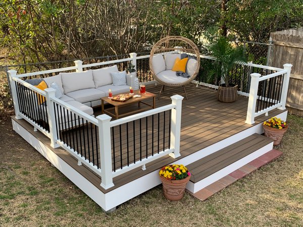 Deck with outdoor furniture and a composite railing lit at early evening. 