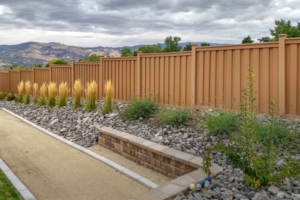 Beautiful brown Trex fence with a lawn and garden. 