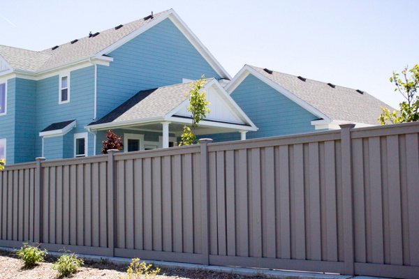 Beautiful brown Trex fence with a lawn and garden. 