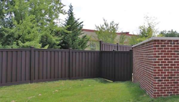 Beautiful brown Trex fence with a lawn and garden. 