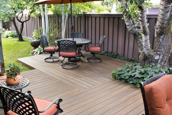 Beautiful brown Trex fence with a lawn and garden. 