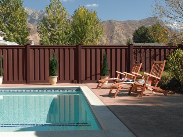 Beautiful brown Trex fence with a lawn and garden. 