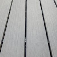 A detailed view of gray composite decking boards arranged in parallel lines. The surface features a textured finish, ideal for outdoor use. The Trex logo is visible in the corner, indicating the brand. The image highlights durability and modern design.