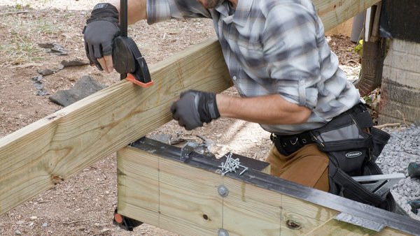 person making sure the side joist is flush with outside edge of beam
