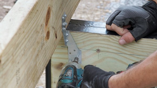 person attaching hurricane tie to the beam