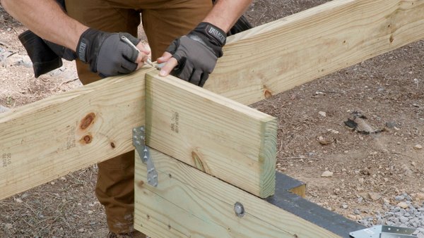 person using a speed square to mark the top of the joist